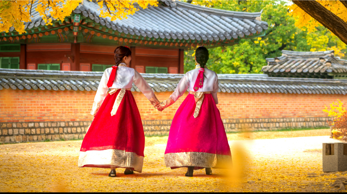 2 women holding hands in traditional Korean attire.